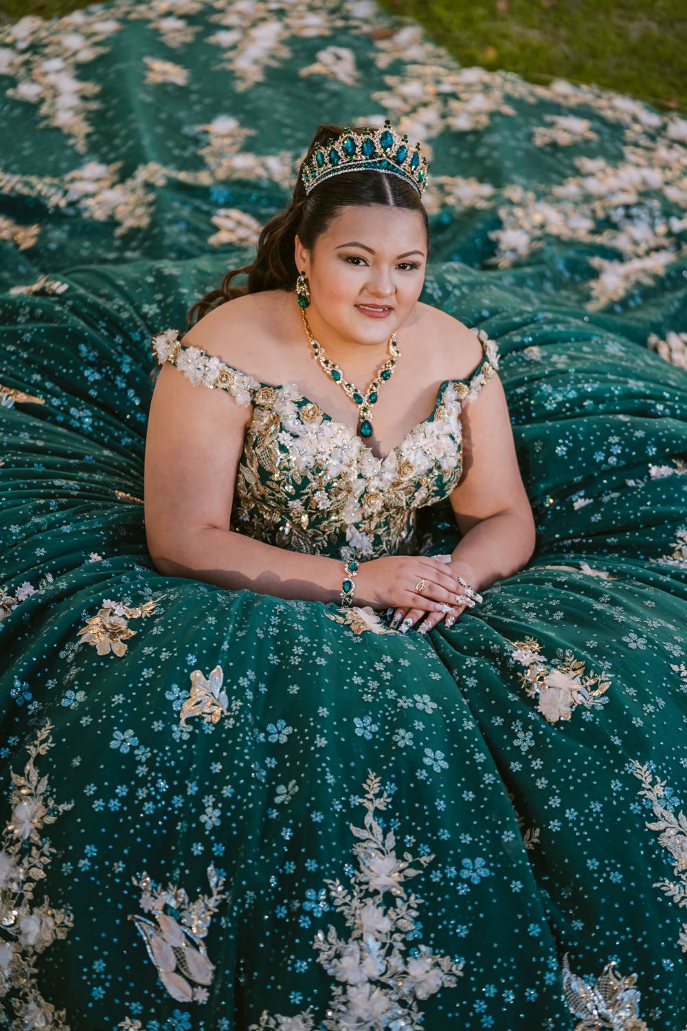 Quinceañera sentada sobre la cola de su vestido verde