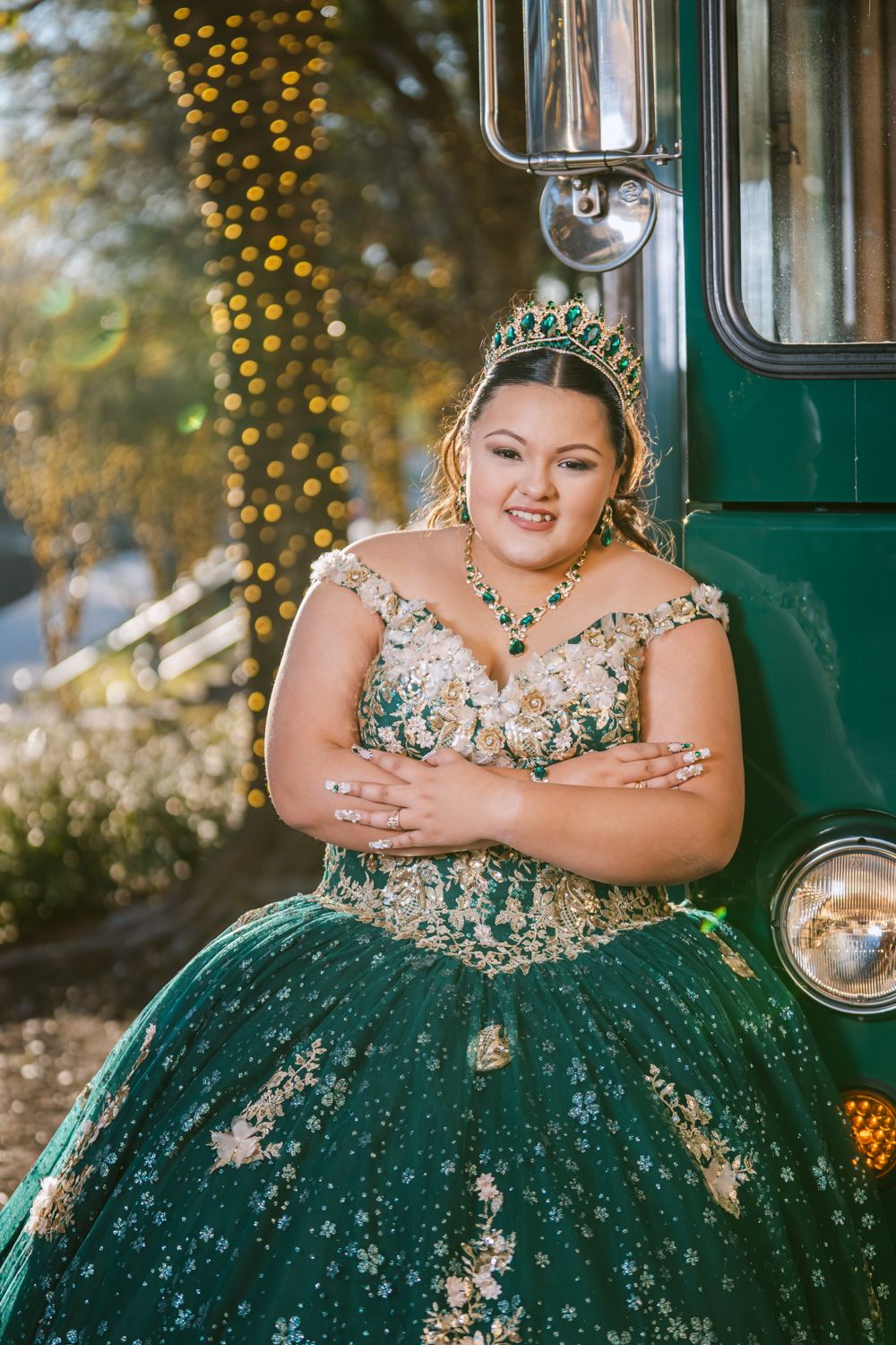 Quinceañera con vestido verde esmeralda junto a un trolley