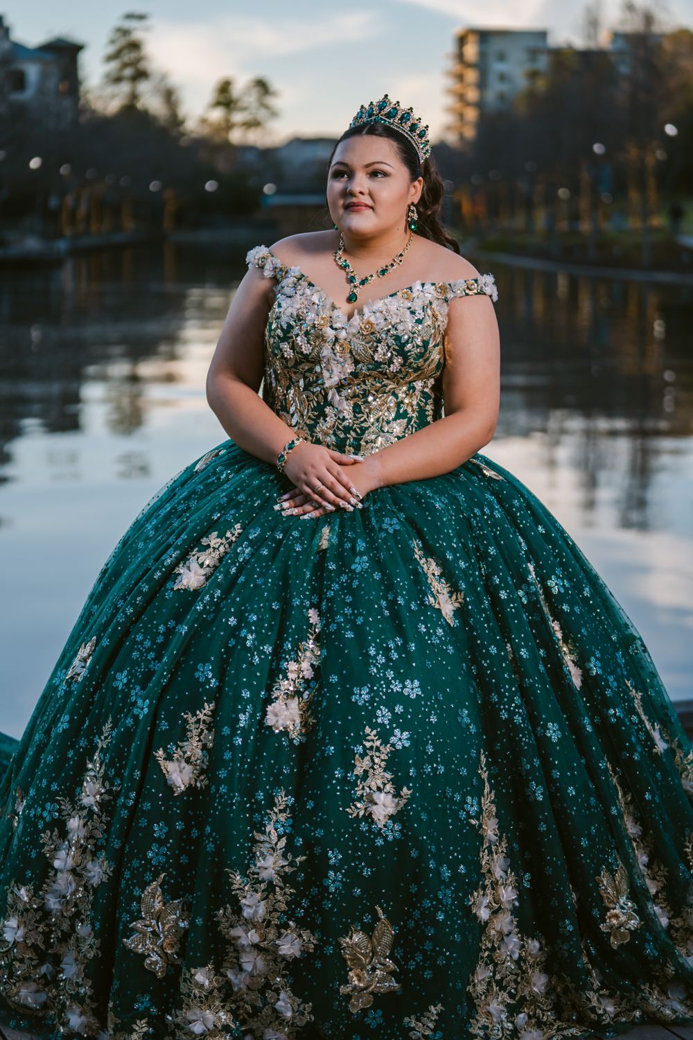 Quinceañera con vestido verde frente a un lago
