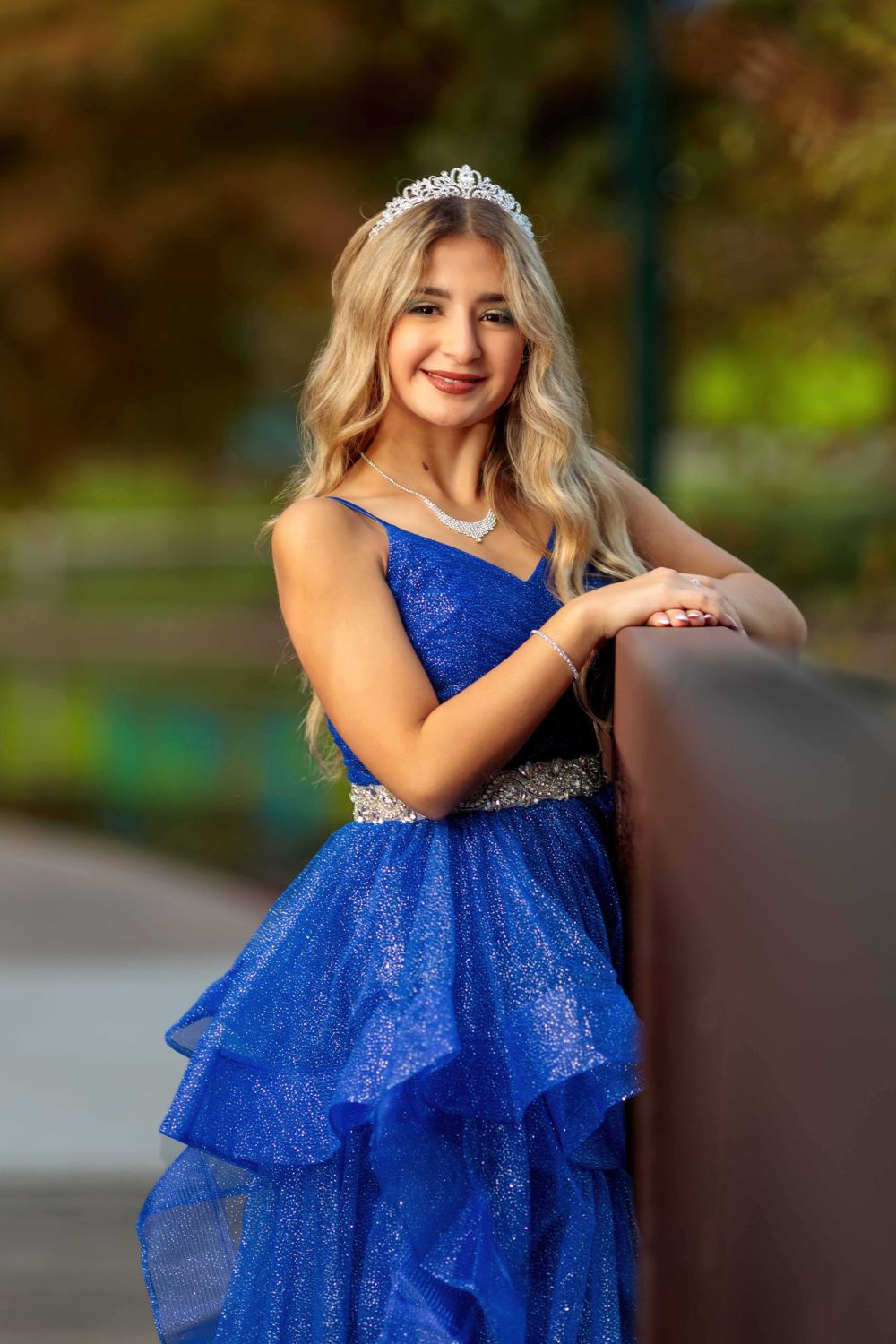 Quinceañera con vestido azul apoyada en una baranda